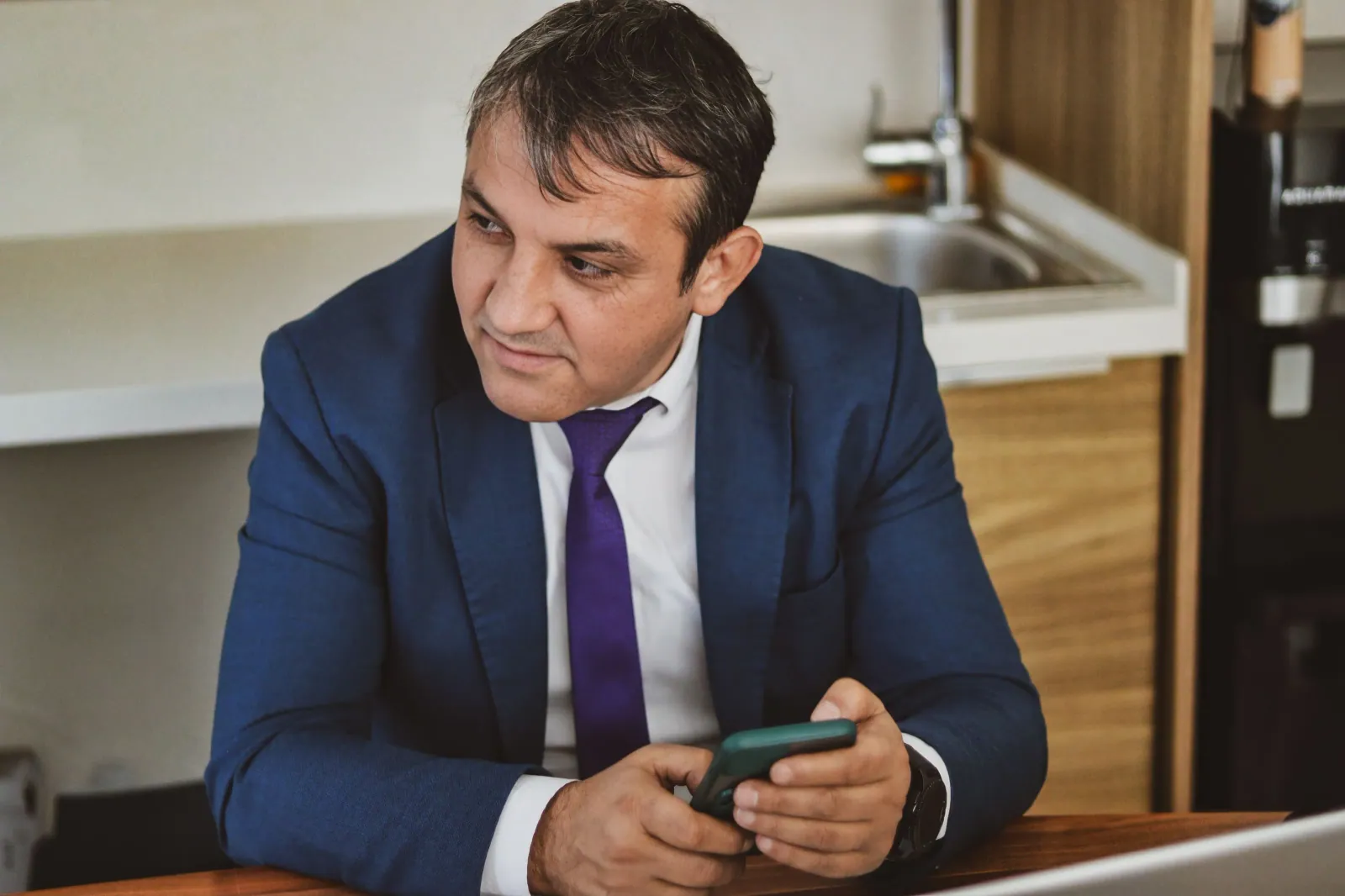 Ofiste akıllı telefonunu kullanan takım elbiseli iş insanı